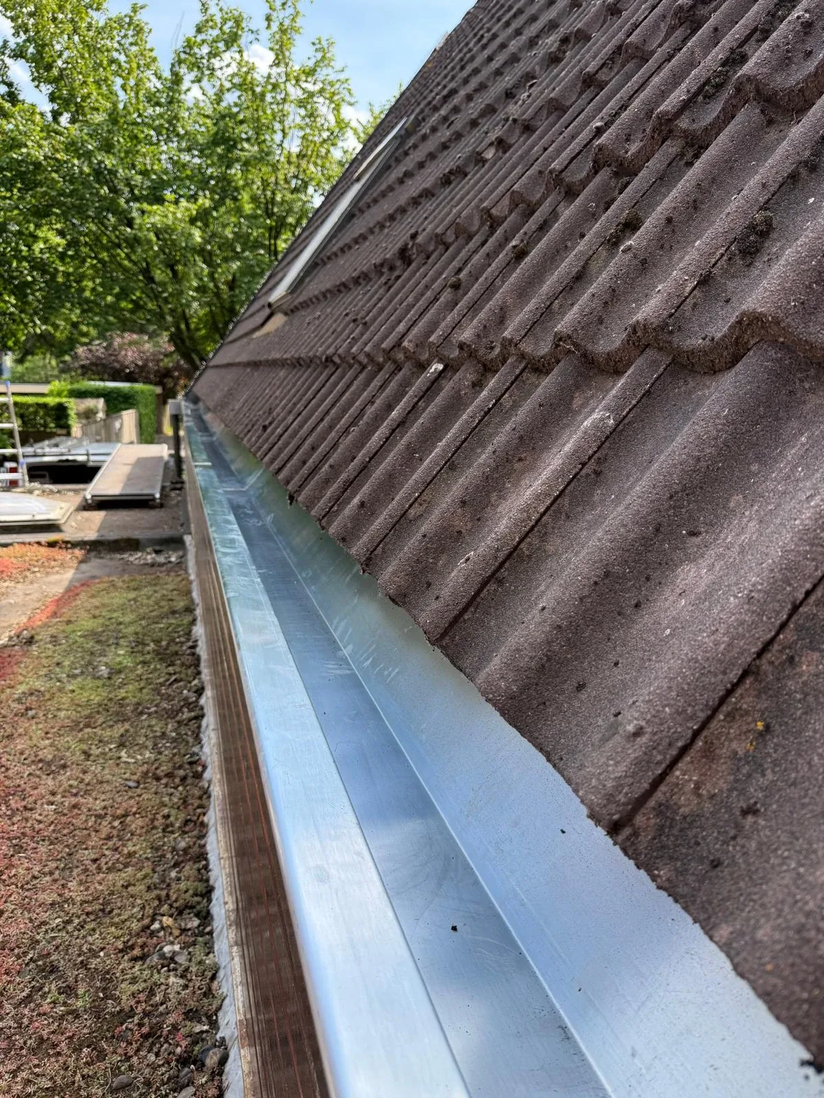 Nieuwe aluminium dakgoot langs de dakpannen